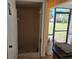 Outdoor shower with light brown tiling, glass door, and adjacent screened patio with exterior access at 2280 Toniwood Ln, Palm Harbor, FL 34685