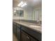 Bathroom featuring double sinks with granite countertops, dark cabinetry, and a large mirror at 2588 Bartolo Dr, Land O Lakes, FL 34639