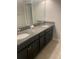 Bathroom featuring double sinks with granite countertops, dark cabinetry, and a large mirror at 2588 Bartolo Dr, Land O Lakes, FL 34639