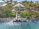 Coastal home featuring a dock and a lift sitting on the water with tropical surrounding and lush greenery at 79 Palm Dr, Placida, FL 33946