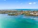 Stunning aerial view of the home nestled on a lush island surrounded by turquoise waters and clear blue skies at 79 Palm Dr, Placida, FL 33946