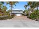 Charming two-story home with a white roof, brick driveway, lush landscaping, and a convenient carport at 79 Palm Dr, Placida, FL 33946