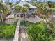 Elevated coastal home with a screened porch, stairway access, and surrounded by lush tropical greenery and white sands at 79 Palm Dr, Placida, FL 33946