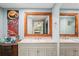 Bathroom with double vanity and a wooden framed mirror, with art and a peek into bedroom at 8537 Cameo Dr, New Port Richey, FL 34654