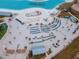 Stunning aerial view of the community lagoon with white sand, palm trees and many lounge chairs for residents at 11307 Linden Depot Rd, San Antonio, FL 33576