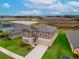 Aerial view of a home with a lawn, neighboring houses, and scenic pond in a tranquil setting at 11307 Linden Depot Rd, San Antonio, FL 33576