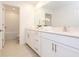 A full bathroom featuring white cabinetry, double sinks, quartz countertops, and decorative floral arrangements at 11307 Linden Depot Rd, San Antonio, FL 33576