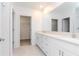 This bathroom features double sinks, white cabinets, quartz countertops, and a doorway to a walk-in closet at 11307 Linden Depot Rd, San Antonio, FL 33576