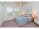 Comfortable bedroom featuring a ceiling fan, two windows, and a stylish upholstered bed with blue accents at 11307 Linden Depot Rd, San Antonio, FL 33576