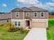 Two-story house with a two-car garage, landscaped front yard, and charming architectural details at 11307 Linden Depot Rd, San Antonio, FL 33576