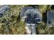 Aerial view of a well-maintained home with a large roof, surrounded by lush trees and a neatly kept lawn at 12411 Cavalier Ct, Hudson, FL 34669