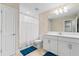 Clean bathroom with blue rugs, large mirror, and white cabinets at 12854 Boggy Creek Dr, Riverview, FL 33579