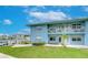Waterfront multifamily home with a grass lawn, dock and patio space, under a blue sky at 300 Venetian Dr # 7, Clearwater, FL 33755