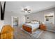 Comfortable bedroom with wood-look flooring, a ceiling fan, and natural light from two windows at 19891 Bridgetown Loop, Venice, FL 34293