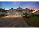 Beautiful exterior elevation with brick driveway, three-car garage, stone accents and professional landscaping at 19891 Bridgetown Loop, Venice, FL 34293