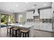 A view of the kitchen with an island that includes bar seating, quartz countertops, and a dining area by the sliding glass doors at 19891 Bridgetown Loop, Venice, FL 34293