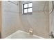 Close up on a tub and tiled shower with a window and shower head, creating a bright, clean bathroom space at 3369 Houle Ave, Sarasota, FL 34232