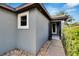 Home entrance with a gray exterior, white-framed window, trimmed shrubbery and a pebble walkway under a blue sky at 3369 Houle Ave, Sarasota, FL 34232