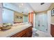 Bathroom with wood cabinets, countertop, large mirror, and glass-enclosed shower and tub at 36750 Us Highway 19 # 21-301, Palm Harbor, FL 34684