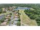 Aerial view of neighborhood homes next to golf course and lake, surrounded by lush trees at 394 Tall Oak Trl, Tarpon Springs, FL 34688