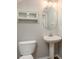Cozy powder room featuring a pedestal sink, oval mirror, and storage cabinet at 8907 Casablanca Way, Tampa, FL 33626