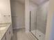 Bright bathroom featuring a glass-enclosed shower, granite countertop and gray, wood-look flooring at 13290 Ogden Glade Rd, Dade City, FL 33525
