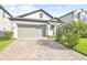 Charming home featuring a brick driveway, two-car garage, and tropical landscaping at 18015 Fenders Way, Land O Lakes, FL 34638