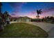 Charming single-story home with well-maintained lawn, spacious driveway and beautiful sky at sunset at 1022 Canal St, Ruskin, FL 33570