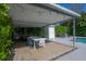 Outdoor dining area featuring a modern table, chairs, and string lights under a covered patio with lush greenery at 3611 W De Leon St, Tampa, FL 33609