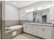 Spacious bathroom with a soaking tub, dual sink vanity, and modern lighting at 422 Shannon Estates Ct, Plant City, FL 33563