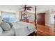 Bright main bedroom featuring four-poster bed, hardwood floors, and water view through sliding glass doors at 6423 Driftwood Dr, Hudson, FL 34667