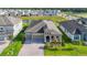 Aerial view of a single-story home with a brick driveway, neutral stucco, three-car garage, landscaping, and pond view at 13028 Homestead Ln, Parrish, FL 34219