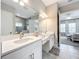 Bright bathroom featuring double sinks, white cabinetry, and a view to the bedroom at 13028 Homestead Ln, Parrish, FL 34219