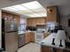 Well-lit kitchen boasts stainless steel appliances, wooden cabinetry and tiled flooring at 255 Capri N Cir # 17, Treasure Island, FL 33706
