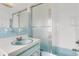 Retro bathroom features a step-in shower with glass door, blue sink and cabinet at 4902 Stolls Ave, Tampa, FL 33615