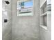 Modern bathroom shower with marble tile, built in shelves, and window at 3009 E 148Th Ave # B, Lutz, FL 33559