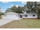 Charming single-story home showcasing a brick and light gray exterior, two-car garage, manicured landscaping, and welcoming red door at 11592 110Th Ter, Seminole, FL 33778