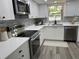 Modern kitchen featuring stainless steel appliances, white cabinets and white quartz countertops and gray backsplash at 11592 110Th Ter, Seminole, FL 33778