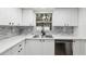 A modern kitchen with white cabinets, gray backsplash, and stainless steel appliances at 11592 110Th Ter, Seminole, FL 33778