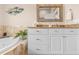 Bathroom with a bathtub and white vanity featuring granite countertops and decorative mirror at 8731 Betty St, Port Richey, FL 34668
