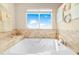 Luxury bathroom featuring a deep soaking tub with jets, tile surround, and natural light, perfect for relaxation at 8731 Betty St, Port Richey, FL 34668