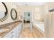 Bright bathroom featuring double vanity with granite countertops, framed mirrors, and a soaking tub at 8731 Betty St, Port Richey, FL 34668