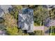 Aerial view showcasing the house with a gray roof and screened-in pool surrounded by mature trees at 2850 Deer Run, Tarpon Springs, FL 34688