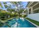 Sunlit backyard showcasing a refreshing pool and a spacious lawn, complemented by the home's architecture at 5038 W Dickens Ave, Tampa, FL 33629