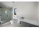 Modern bathroom featuring glass shower, gray vanity with white counter, black hardware, and a large window at 5038 W Dickens Ave, Tampa, FL 33629