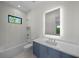 Bright bathroom featuring a blue vanity with a white countertop, a soaking tub, and a window at 5038 W Dickens Ave, Tampa, FL 33629