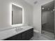 Bathroom with a large, lighted mirror, dual-sink vanity, and glass walk-in shower at 5038 W Dickens Ave, Tampa, FL 33629