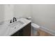 Powder room featuring marble countertop, dark cabinets, black hardware, and wood floors at 5038 W Dickens Ave, Tampa, FL 33629