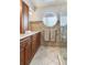 Bathroom featuring double sinks, wood cabinets, granite counter tops, shower and round accent window at 16134 4Th E St, Redington Beach, FL 33708