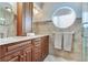 Bathroom featuring double sinks, wood cabinets, granite counter tops, shower and round accent window at 16134 4Th E St, Redington Beach, FL 33708